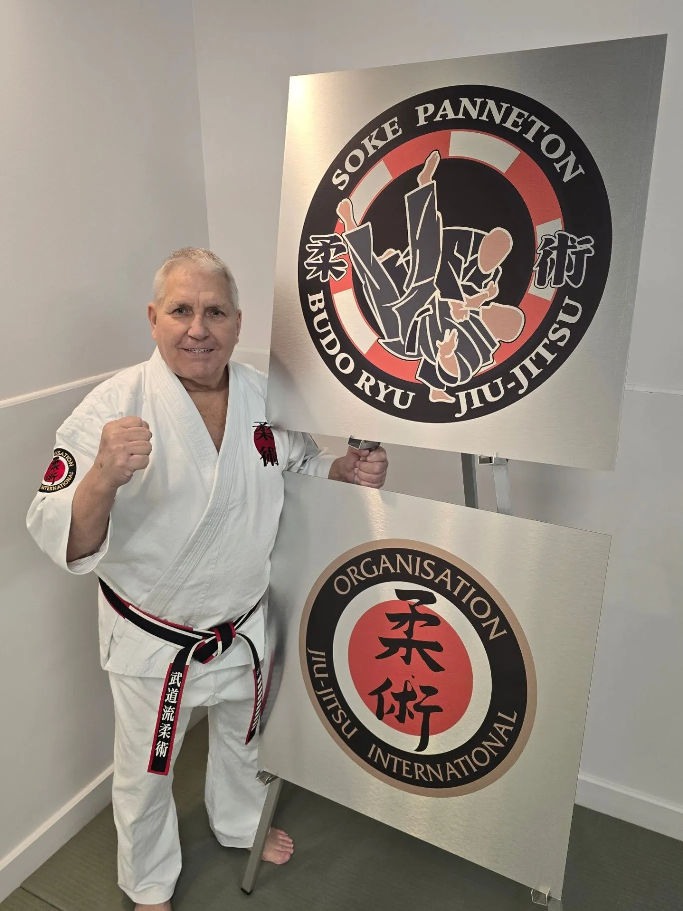 Soke Robert Panneton in a white gi beside the Budo-Ryu and OJI crests